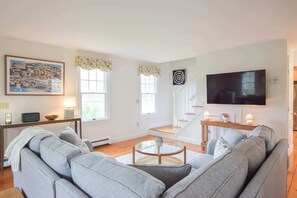 A living room with a sofa, a coffee table, a TV, and a staircase.