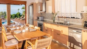 Cocina moderna con comedor, vista a la piscina y un amplio ventanal con cortinas.