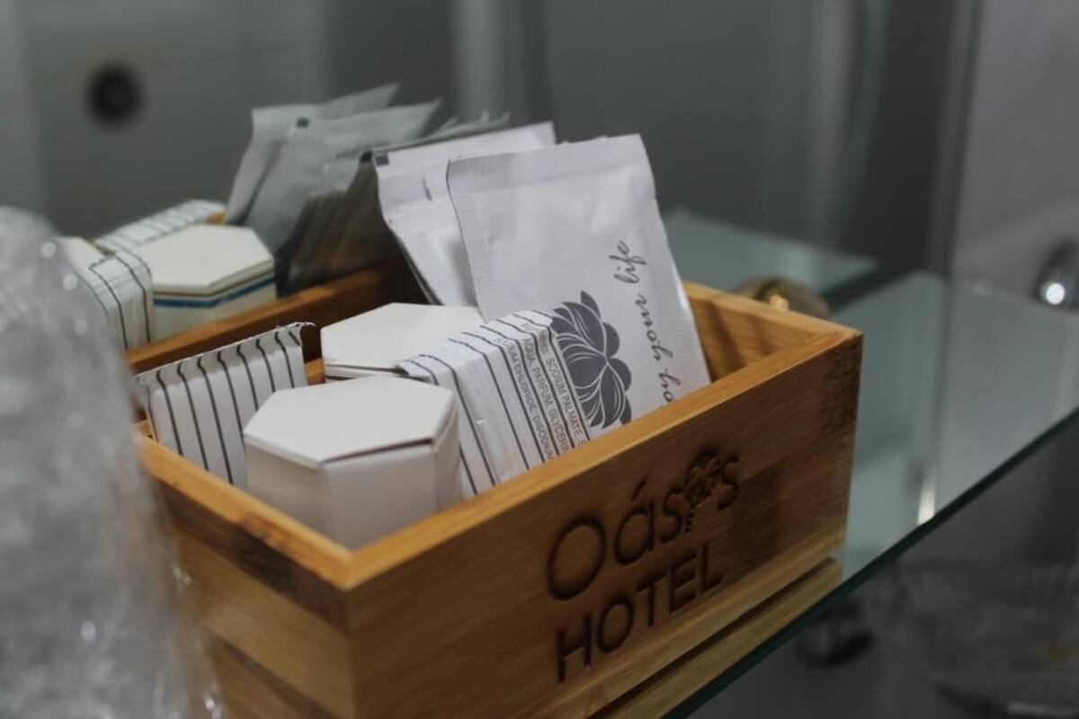 A wooden box labeled "Oásis Hotel" containing various items including a white object and a card with text.
