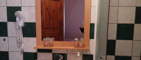 A bathroom with a white sink, a wooden cabinet, a mirror, and a hairdryer.
