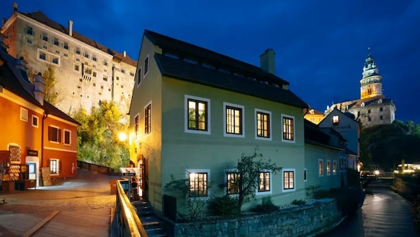 A historic building with a stone facade, multiple windows, and a well-lit entrance. - Penzion Albatros (Cesky Krumlov)