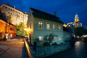 Un edificio histórico con fachada de piedra, múltiples ventanas y una entrada bien iluminada.