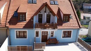 A two-story house with a red-tiled roof, a balcony, and a small garden area. - Penzion Albatros (Cesky Krumlov)