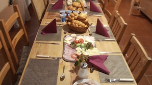 A long dining table set for a meal with various dishes, including bread, salads, and a cake. - Penzion Albatros (Cesky Krumlov)