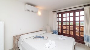 Een hotelkamer met een bed, een raam met gordijnen, een stoel en een airconditioning.