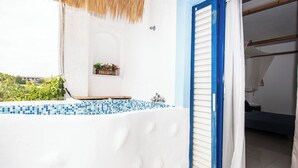 A white exterior wall with a blue door and a small window with a plant. - Ov Suites (Hersonissos)