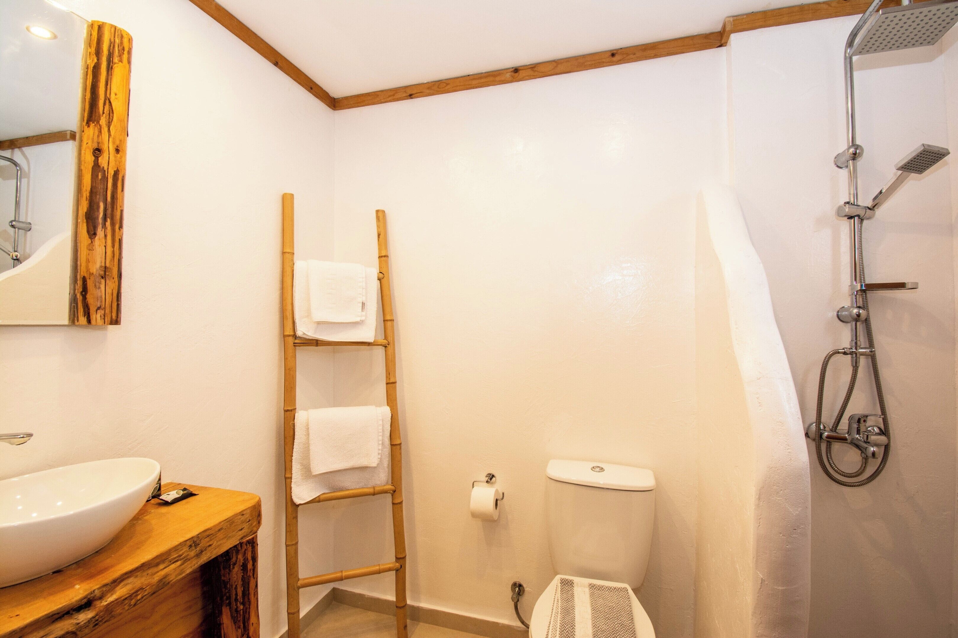 Un baño con tocador de madera, inodoro, ducha y perchero para toallas.