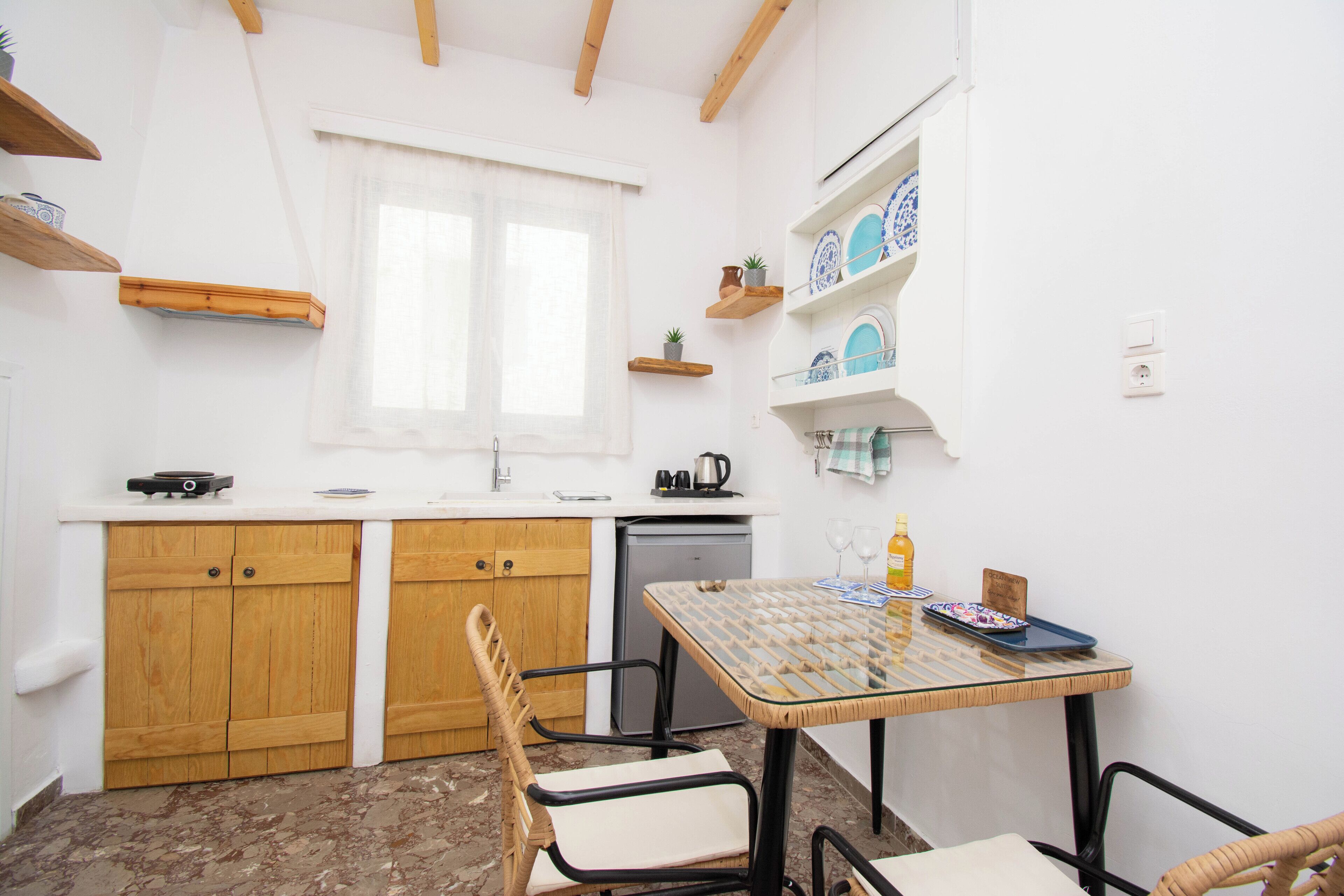 Una cucina compatta con mobili in legno, un piccolo tavolo da pranzo e una finestra con tende leggere.