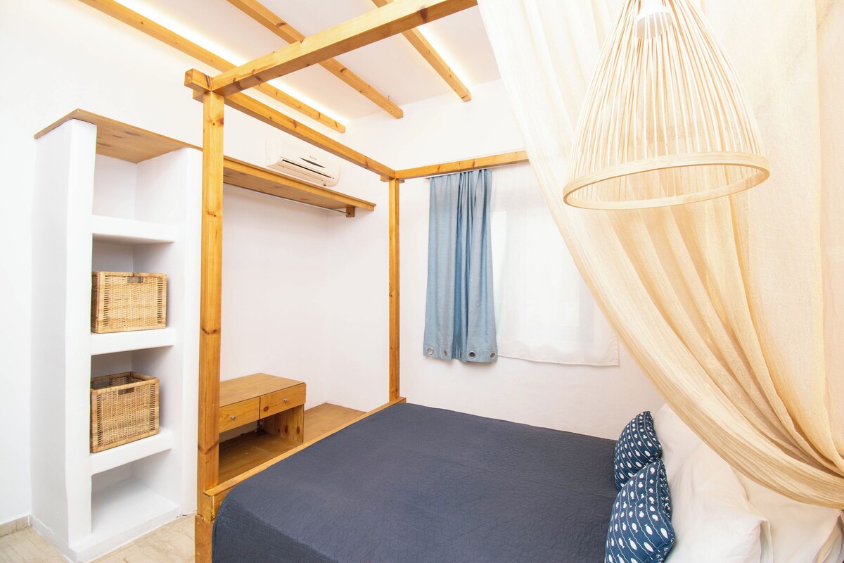 A bedroom with a bunk bed, wooden shelves, a bench, and a hanging light fixture.