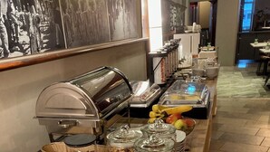 Un bufé con diversas opciones de comida, como pan, frutas y granola.