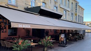 Un café llamado 'DE BEREN' con terraza y una pizarra de menú.