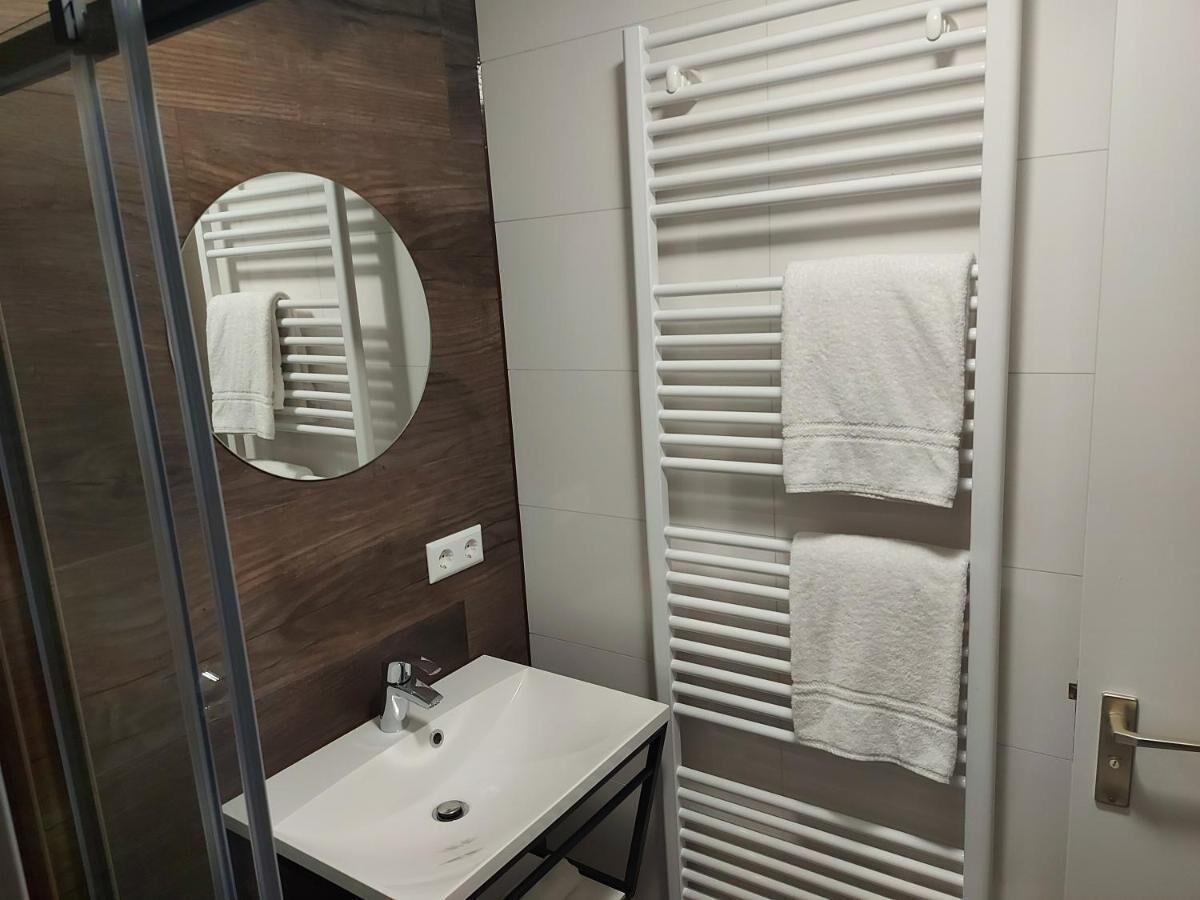 A bathroom with a white sink, a mirror, and a towel rack with towels.