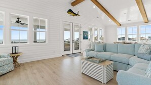 A spacious living room with a light blue sofa, a wooden coffee table, and a ceiling fan.