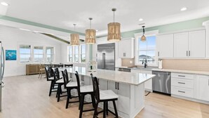 A modern kitchen with white cabinets, a large island, and pendant lighting.