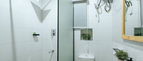 A modern bathroom with a glass shower enclosure, a white sink, and a mirror.