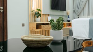 A modern living room with a glass coffee table, a woven bowl, a potted succulent, and a flat-screen TV mounted on the wall. - Kashco Apartment Wuse II (Abuja)