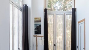 A modern room with a black sofa, a standing lamp, and a large window with curtains. - Agora Apartments   Sea View Apartment (Sorrento)
