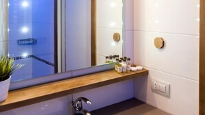 A modern bathroom with a large mirror, a sink, and a shower area.