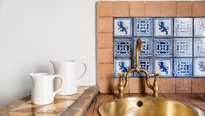 A kitchen with a brass sink, white pitchers, and blue and white patterned tiles. - Agora Apartments Armida street view (SORRENTO)