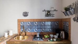 A kitchen with a tiled backsplash, a sink, a gas stove, and various kitchen items. - Agora Apartments Armida street view (SORRENTO)