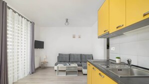 A modern kitchen with yellow cabinets, a black countertop, and a stainless steel sink. - Modern Studio with Balcony | Close to Nature (Katowice)