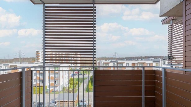 A balcony with a view of a residential area, metal railings, and a clear sky. - Modern Studio with Balcony | Close to Nature (Katowice)