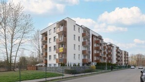 A multi-story residential building with balconies, a fenced courtyard, and a clear sky. - Modern Studio with Balcony | Close to Nature (Katowice)