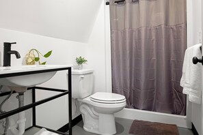 Baño con lavamanos blanco, grifo negro, inodoro y cortina de ducha.