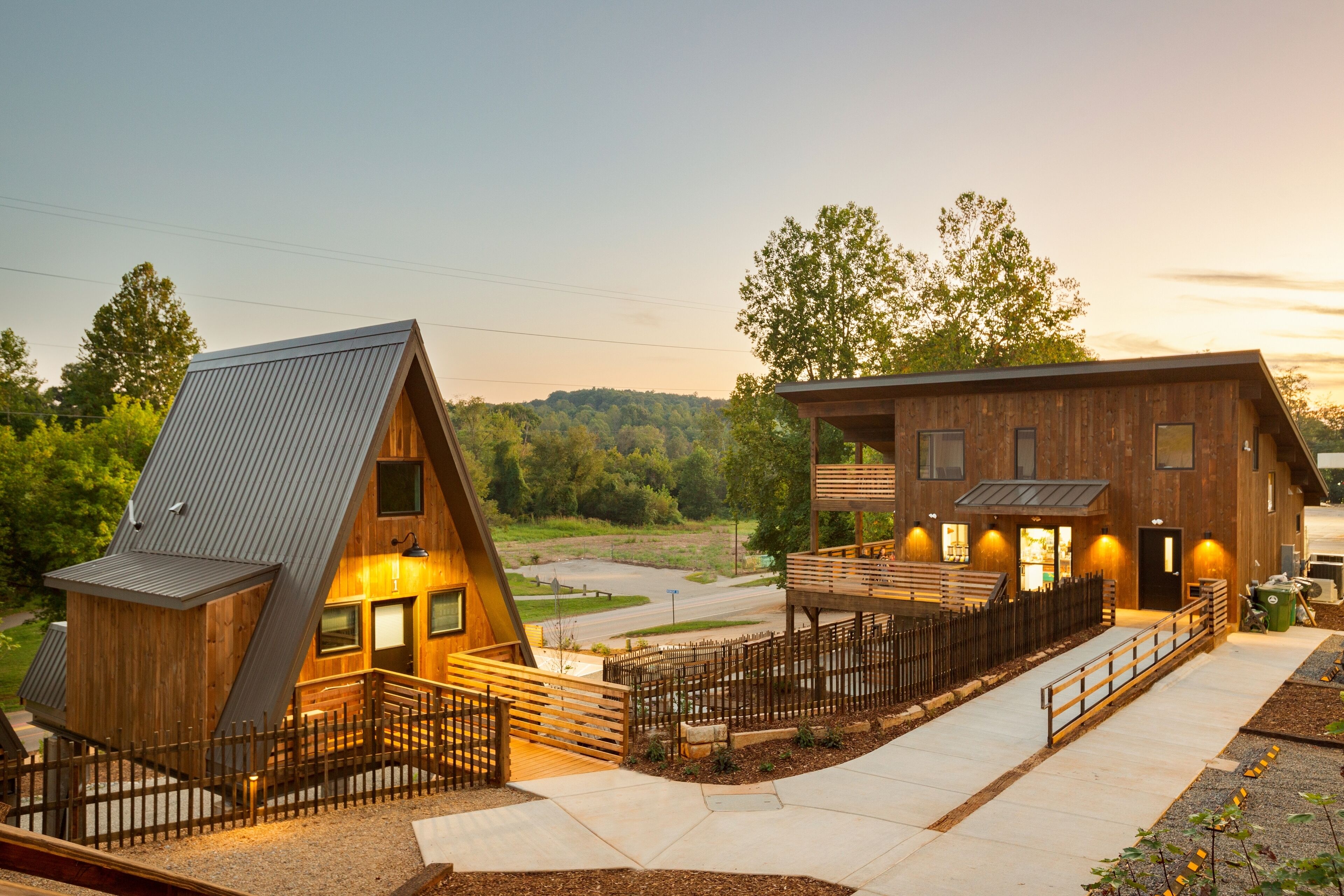 A modern cabin-style building with a sloped roof and wooden exterior, connected to a larger structure with a flat roof.