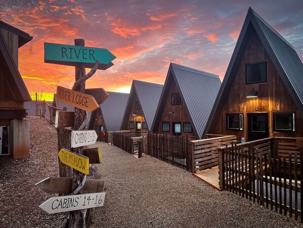 Zona de cabañas de madera con señalización que indica River Lodge, El Prado y las cabañas 2-13, 14-16.