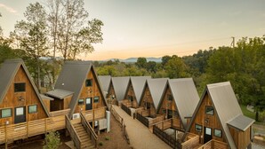 A row of wooden cabins with sloped roofs, arranged in a linear fashion with a central walkway. - Wrong Way River Lodge & Cabins (Asheville)