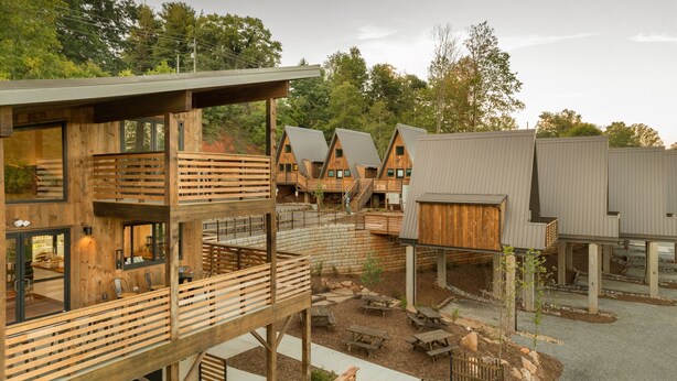 A modern building with multiple wooden structures, outdoor seating, and a natural surrounding. - Wrong Way River Lodge & Cabins (Asheville)