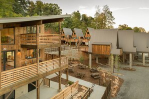 Un edificio moderno con varias estructuras de madera, asientos al aire libre y entorno natural.