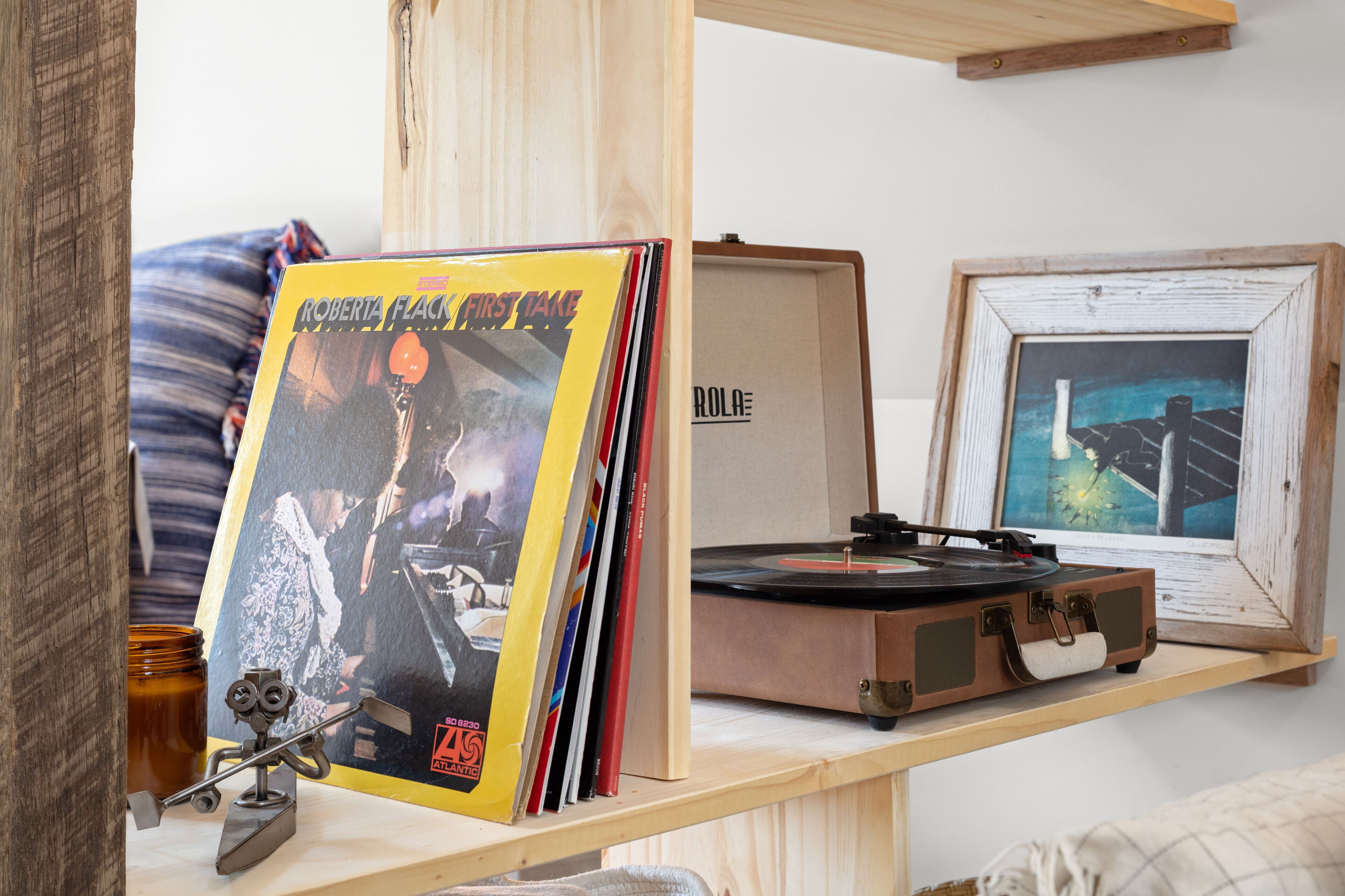 A wooden shelf with a vinyl record, a turntable, and framed pictures.