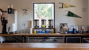 A kitchen with a coffee station, including a coffee machine, grinders, and coffee bags. - Wrong Way River Lodge & Cabins (Asheville)