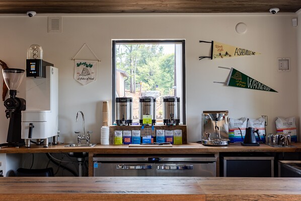 Una cocina con estación de café, que incluye una cafetera, molinillos y paquetes de café.