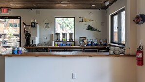 A spacious room with a wooden floor, a counter with various items, and a large window. - Wrong Way River Lodge & Cabins (Asheville)