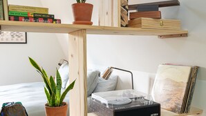 A multi-level wooden shelf unit with potted plants, books, and decorative items. - Wrong Way River Lodge & Cabins (Asheville)