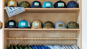 A wooden shelf with hats and a mug, a rack of folded shirts, and a sign for 'Wrong Way River Lodge & Cabins'.