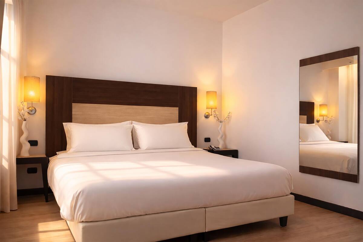 Une chambre d’hôtel avec un grand lit, des lampes de chevet, une table de chevet et un miroir au mur.