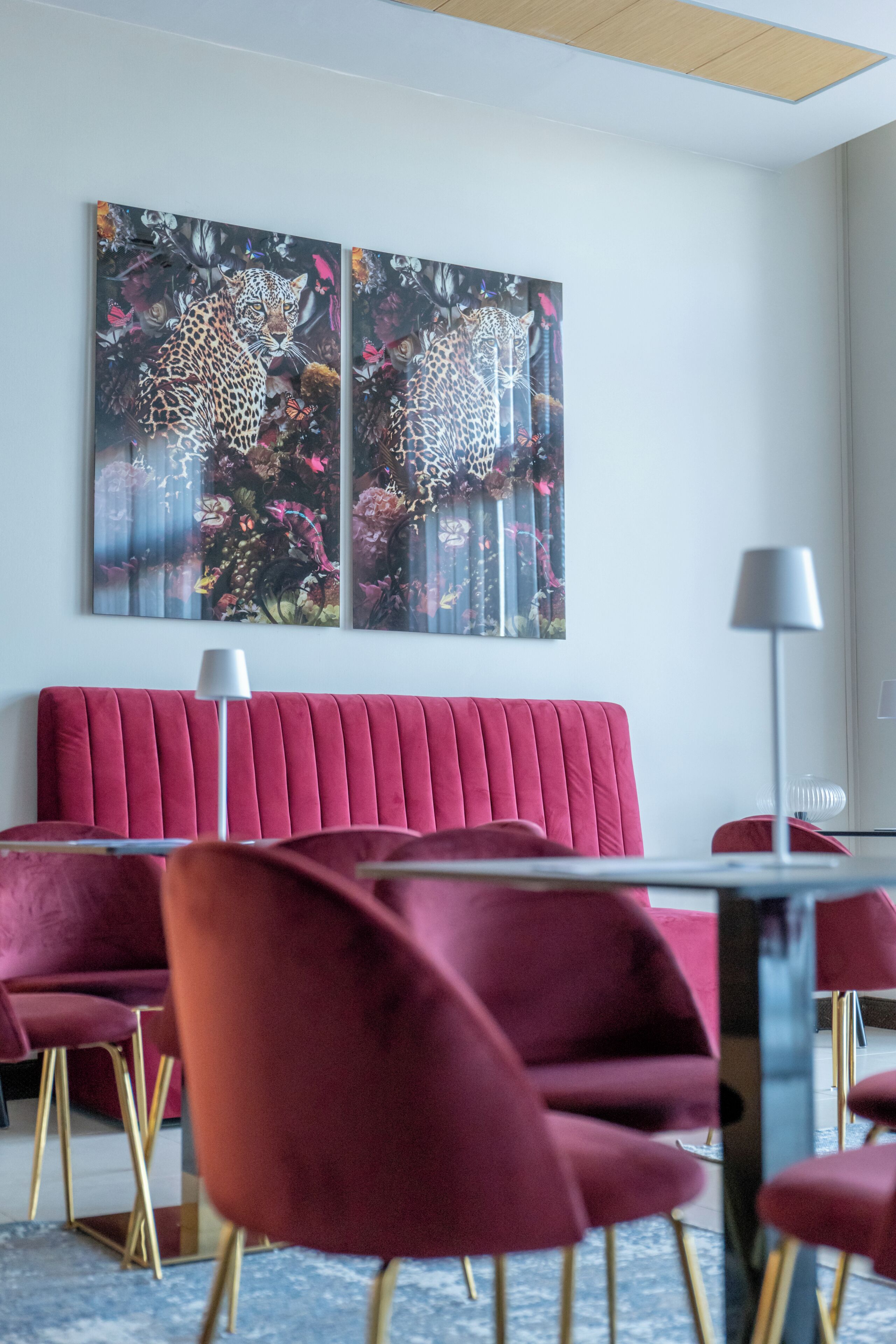 A modern interior with a red upholstered sofa, matching chairs, and a large abstract painting on the wall.