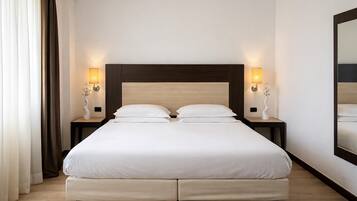 A double bed with a wooden headboard, two bedside tables with lamps, and a large mirror on the wall.