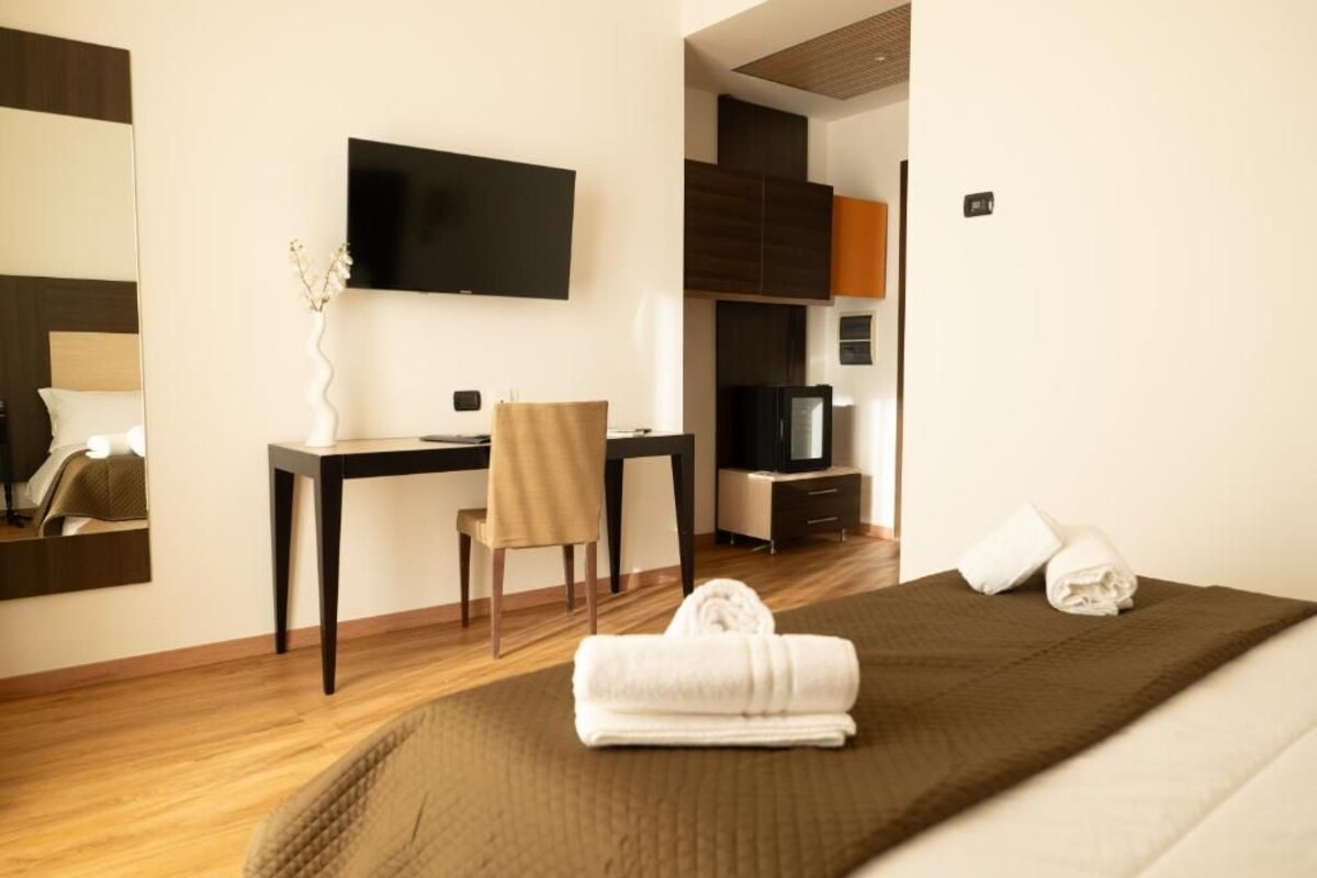 A hotel room with a bed, a desk, a chair, a television, and a mirror.