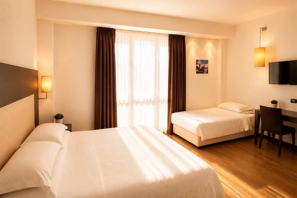 Une chambre d’hôtel avec deux lits, un bureau, une chaise, une télévision et une fenêtre avec des rideaux.