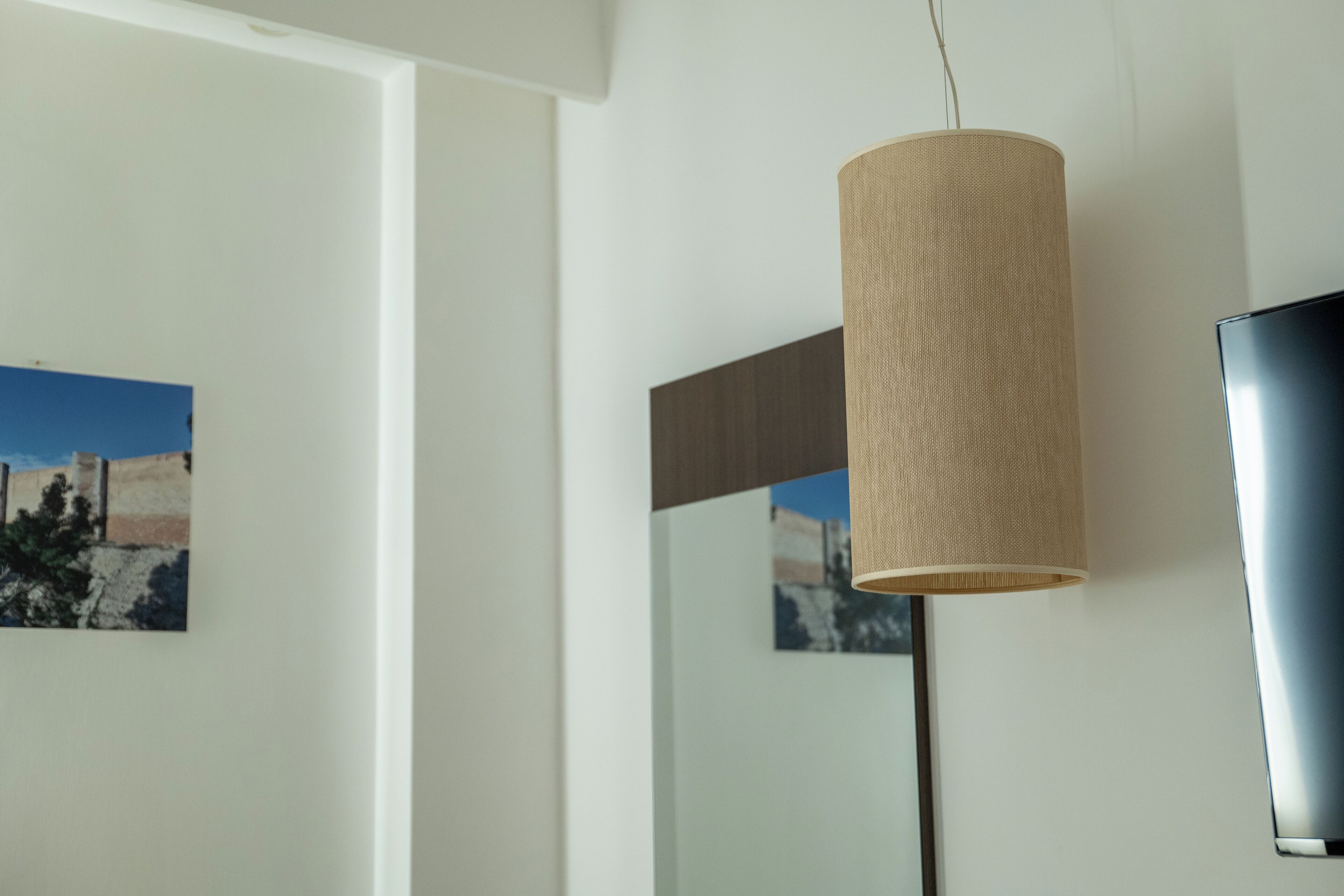 Un interior moderno con una lámpara colgante, un televisor de pantalla plana y un cuadro en la pared.