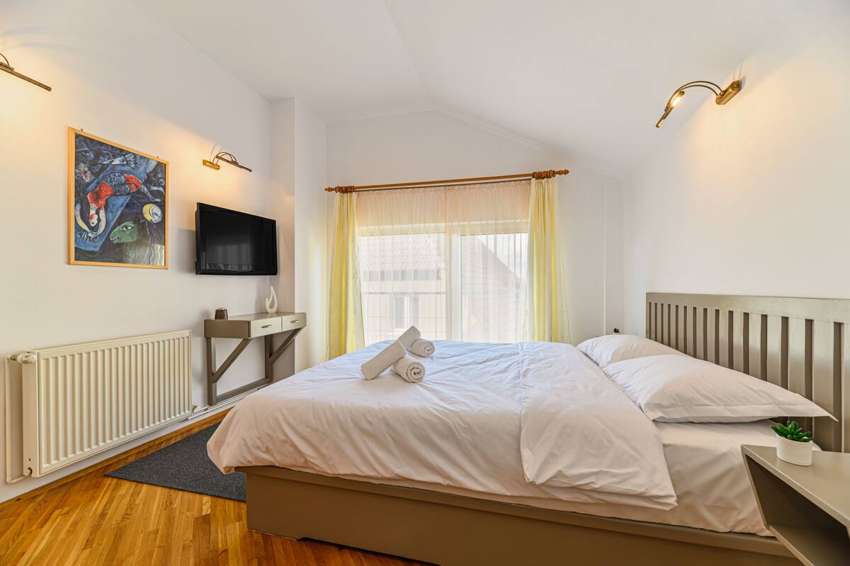 A neatly arranged bedroom with a bed, bedside table, and a mounted TV.
