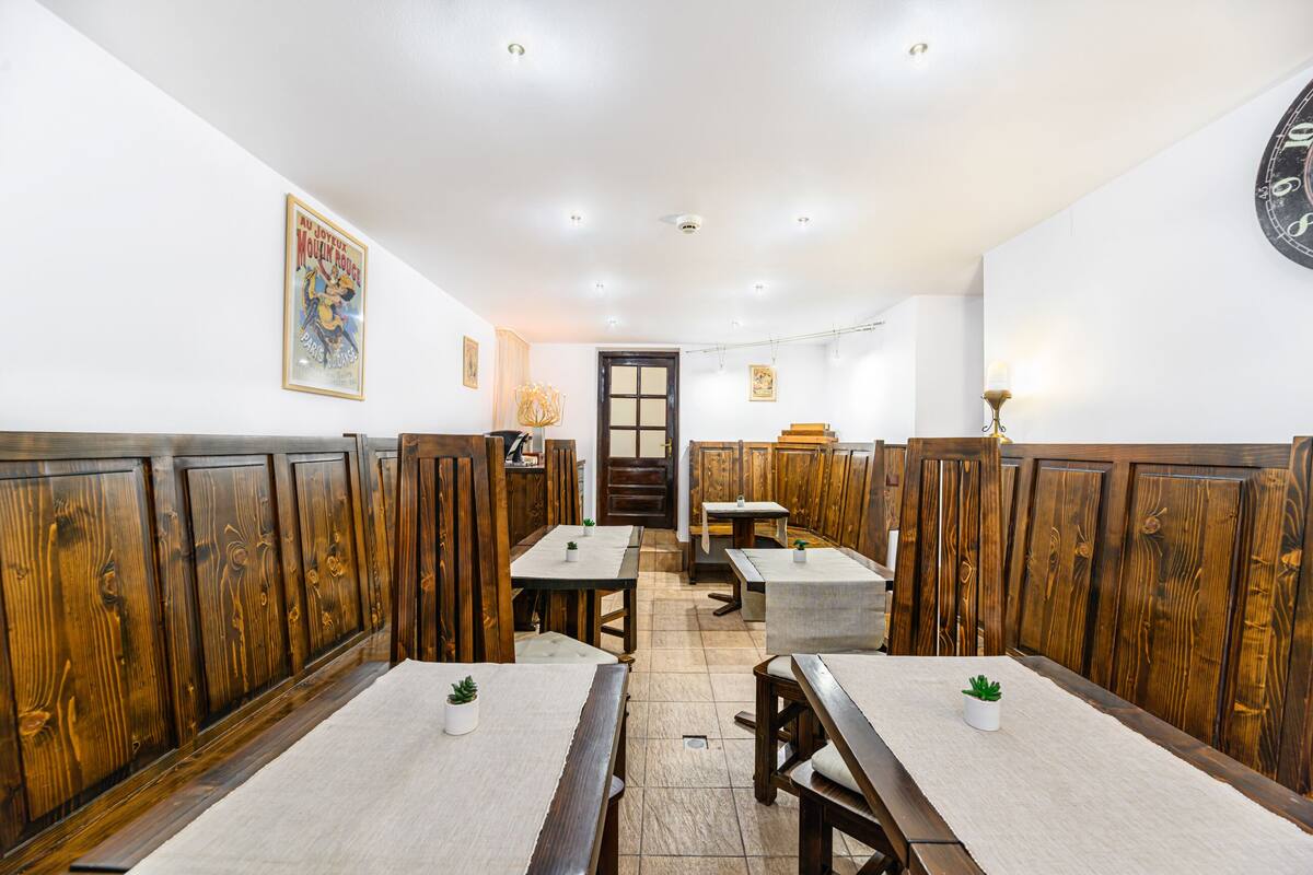 A restaurant with wooden booths, white tables, and a clock on the wall.