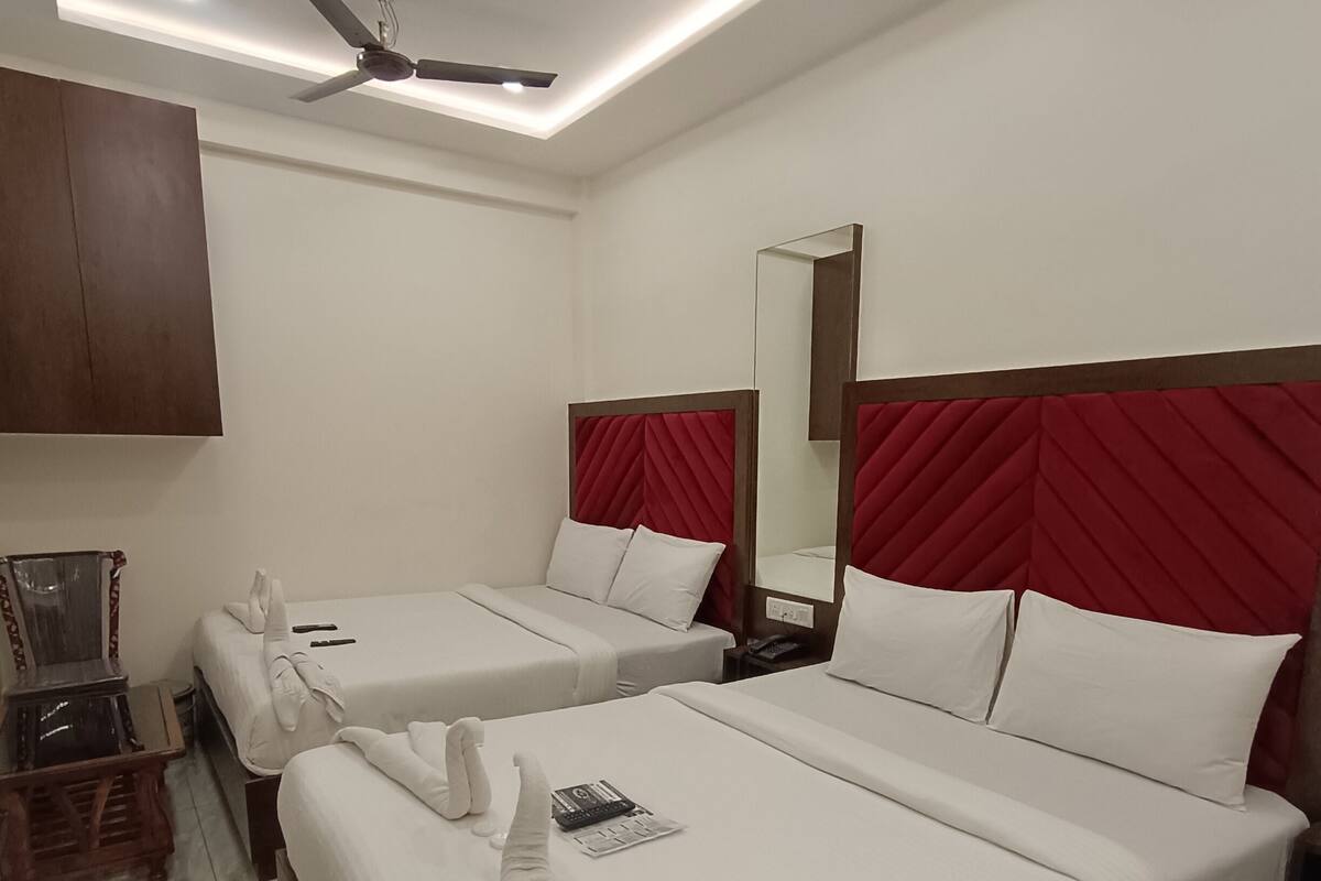 A hotel room with two beds, a ceiling fan, a mirror, and a wooden side table.