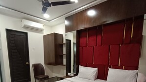 A modern bedroom with a large bed, a ceiling fan, a wardrobe, and a desk. - AR Residency (Mumbai)