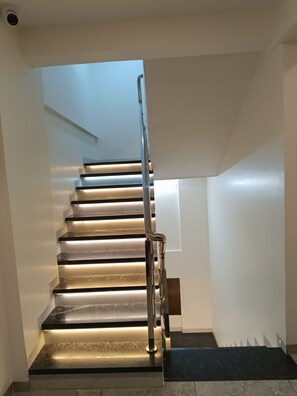 Un escalier moderne avec une rampe métallique et des marches éclairées.